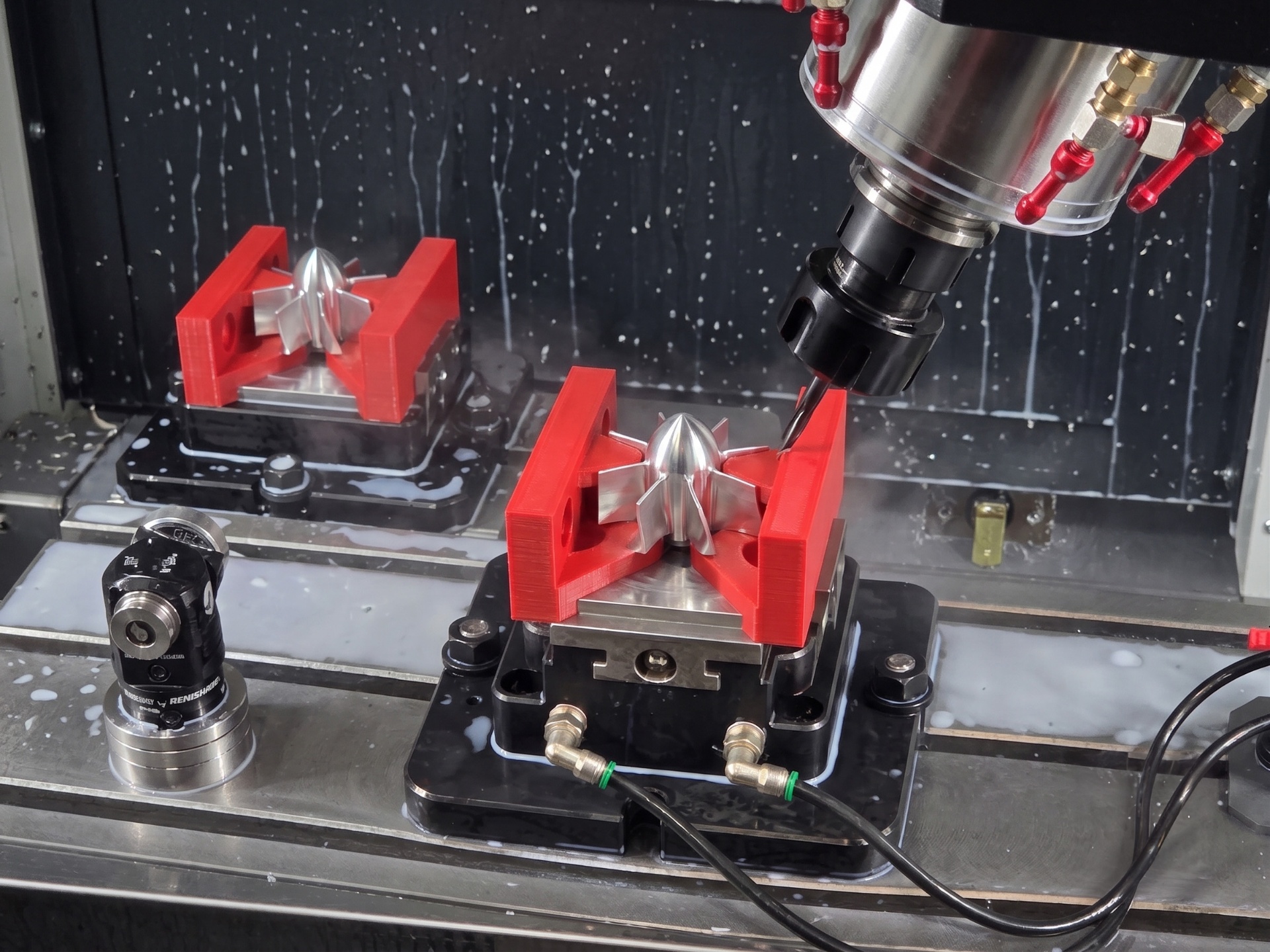 Red 3D-printed soft jaws holding a polished aluminum impeller mid-cut inside a CNC mill