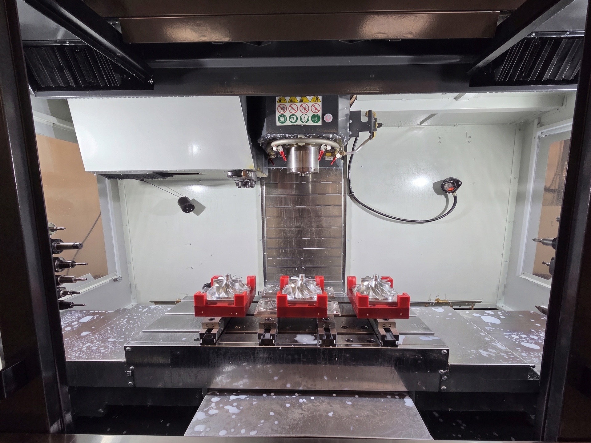 CAD model on a monitor next to the matching machined fixture on a CNC machine